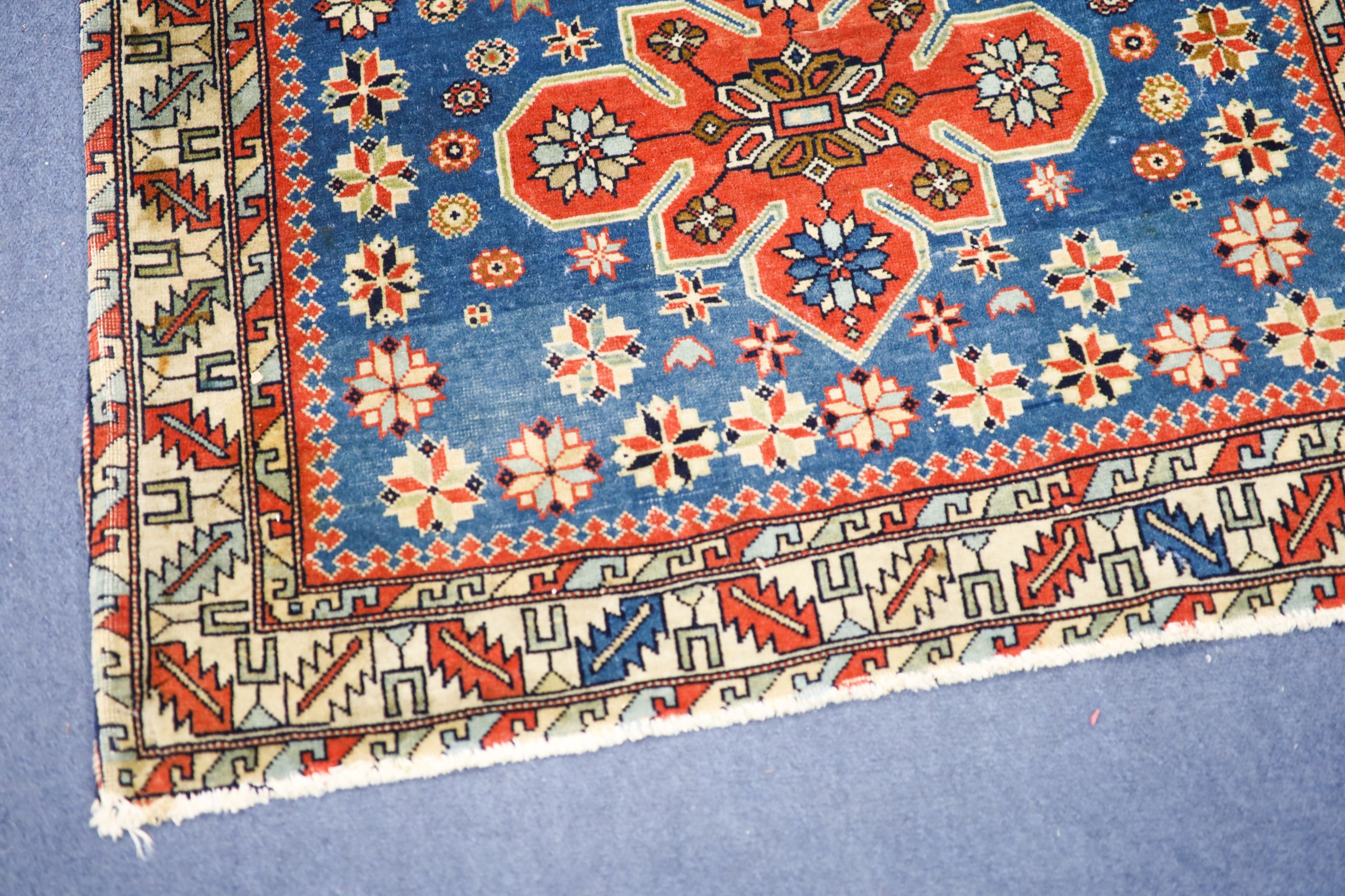 A Caucasian blue ground rug with triple medallions and geometric border, 144 x 89 cm.